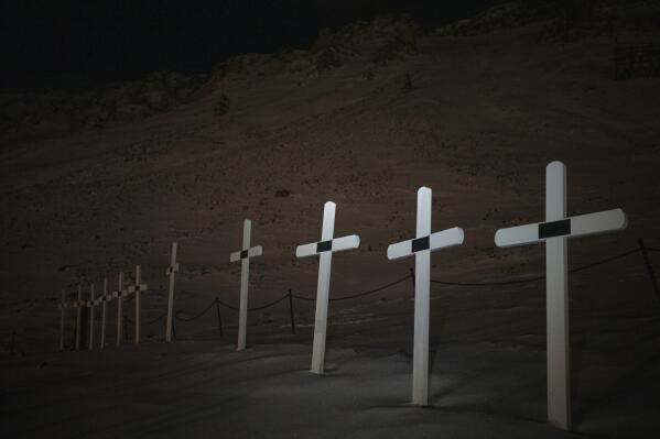 Crosses mark graves at the cemetery in Longyearbyen, Norway, Wednesday, Jan. 11, 2023. The cemetery, established in 1917 for miners -- at least 124 died on duty since then -- is now considered in the "danger zone" from increasing avalanches and landslides. A new burial ground is in the works, though the approximately 30 old graves will not be moved, the Rev. Liv Simstrand said. (AP Photo/Daniel Cole)