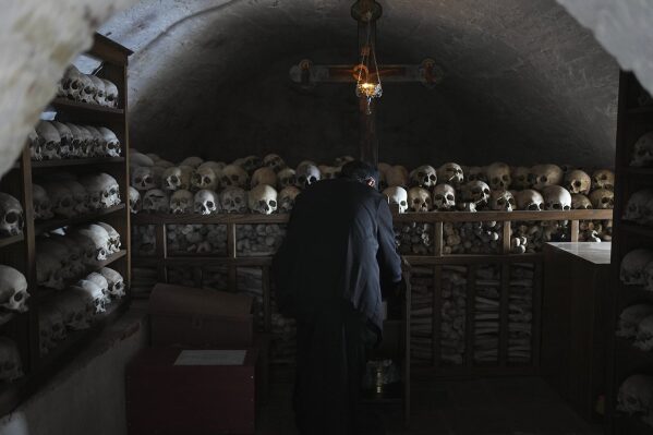 Father Serafeim lights a candle inside an ossuary where the shelves are full of the skulls of the deceased monks of the Simonopetra, or Simonos Petra Monastery, home of the all-male autonomous community of Agion Oros, or Holy Mountain, on the peninsula of Mount Athos in northern Greece, April 14, 2025. (AP Photo/Thanassis Stavrakis)