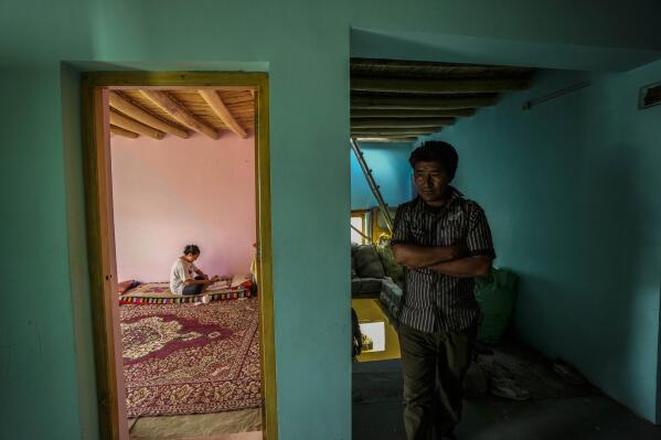 Konchok Dorjey walks toward a room in his home where his daughter Rigzen Angmo reads in Kharnakling near Leh town in the cold desert region of Ladakh, India, Friday, Sept. 16, 2022. (AP Photo/Mukhtar Khan)