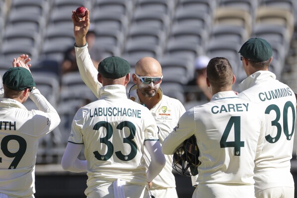 Australia's Nathan Lyon, center, holds the ball aloft after dismissing Pakistan's Faheem Ashraf to claim his 500th test match wicket during play on the fourth day of the first cricket test between Australia and Pakistan in Perth, Australia, Sunday, Dec. 17, 2023. Australia defeated Pakistan by 360 runs. (Richard Wainwright/AAP Image via AP)