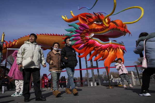 People walk by a giant dragon lantern decorated near the frozen Houhai Lake in Beijing, Thursday, Feb. 8, 2024. Chinese shares rose Thursday as investors appeared to welcome Beijing's choice of an industry veteran to replace its top securities watchdog in its latest effort to boost confidence in ailing markets. (APPhoto/Andy Wong)