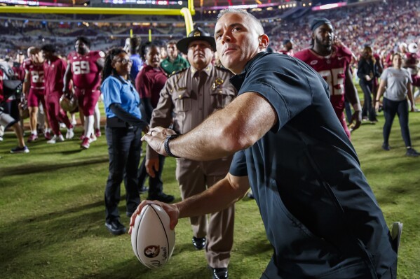 Florida State coach Mike Norvell throws an autographed football to fans in the stands after the team's NCAA college football game against North Alabama, Saturday, Nov. 18, 2023, in Tallahassee, Fla. (AP Photo/Colin Hackley)