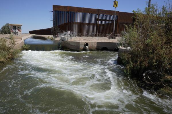 Water from the Colorado River flows in a canal along a border wall separating San Luis Rio Colorado, Mexico with San Luis, Arizona on Sunday, Aug. 14, 2022, in San Luis Rio Colorado, Mexico. By the time the Colorado River reaches Mexico, just a fraction of its water is left for the fields of the Mexicali Valley and millions of people in northwestern desert cities. (AP Photo/Gregory Bull)