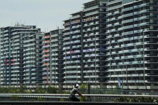 A man rides his bike near the athlete's village for the 2020 Summer Olympics and Paralympics, Thursday, July 15, 2021, in Tokyo. (AP Photo/Jae C. Hong)