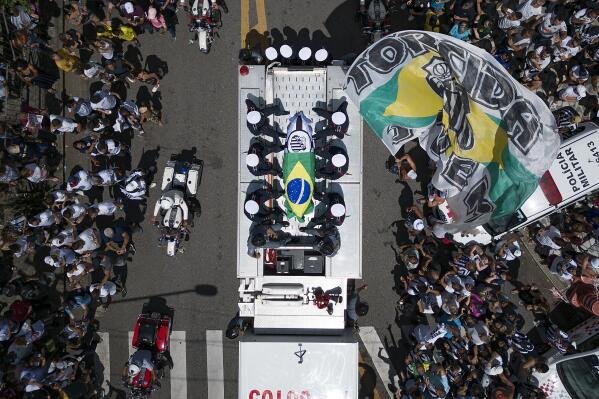 The casket of late Brazilian soccer great Pele is draped in the Brazilian and Santos FC soccer club flags as his remains are transported from Vila Belmiro stadium, where he laid in state, to the cemetery during his funeral procession in Santos, Brazil, Tuesday, Jan. 3, 2023. (AP Photo/Matias Delacroix)