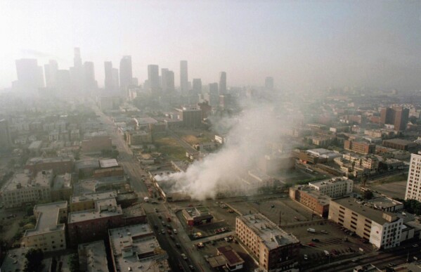 In this April 30, 1992 file photo, smoke rises from a shopping center burned by rioters in Los Angeles after four police officers had been acquitted of the 1991 beating of motorist Rodney King. (AP Photo/Paul Sakuma, File)