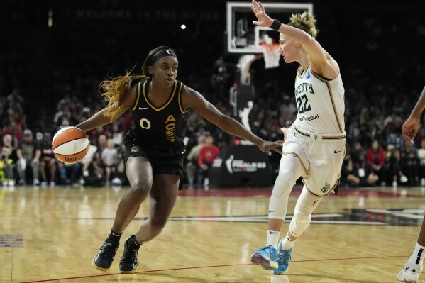 Las Vegas Aces guard Jackie Young (0) drives against New York Liberty guard Courtney Vandersloot (22) during the second half in Game 1 of a WNBA basketball final playoff series Sunday, Oct. 8, 2023, in Las Vegas. (AP Photo/John Locher)