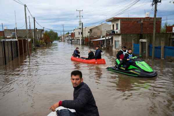 Residents and rescue workers navigate through flooded streets following heavy rains in Campana, Argentina, Saturday, May 17, 2025. (AP Photo/Rodrigo Abd)
