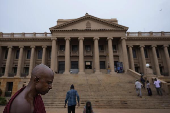 FILE- A Buddhist monk walks past the president's office as he prepares to vacate the premise along with other protestors in Colombo, Sri Lanka, Thursday, July 21, 2022. A Sri Lankan government minister on Wednesday, Aug. 10, submitted to Parliament a constitutional amendment bill that would clip the powers of the president, a key demand of protesters calling for political reforms and solutions to the country's worst economic crisis. (AP Photo/Eranga Jayawardena, File)