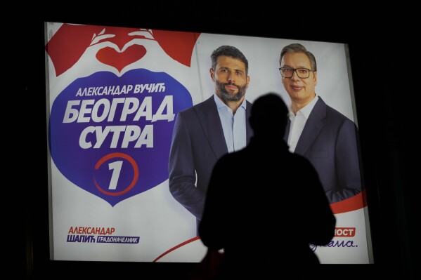A man walks in front of a pre-election billboard showing Serbian President Aleksandar Vucic, right, and Belgrade mayor candidate Aleksandar Sapic in Belgrade, Serbia, Wednesday, May 29, 2024, ahead of the municipal vote set for June 2. Voters in Serbia go to the polls this weekend in a municipal election for dozens of cities and towns, including a rerun vote in the capital Belgrade where ruling populists were accused of a fraud at a previous vote in December. The right-wing Serbian Progressive Party of President Aleksandar Vucic is seen as a favorite ahead of the Sunday balloting which could further secure the strongman's already vast hold on power. (AP Photo/Darko Vojinovic)