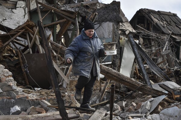 Inna, 71, carries possessions rescued from the rubble of her house which was destroyed by a Russian drone attack in a residential neighbourhood, in Zaporizhzhia, Ukraine, on Thursday, March 28, 2024. (AP Photo/Andriy Andriyenko)