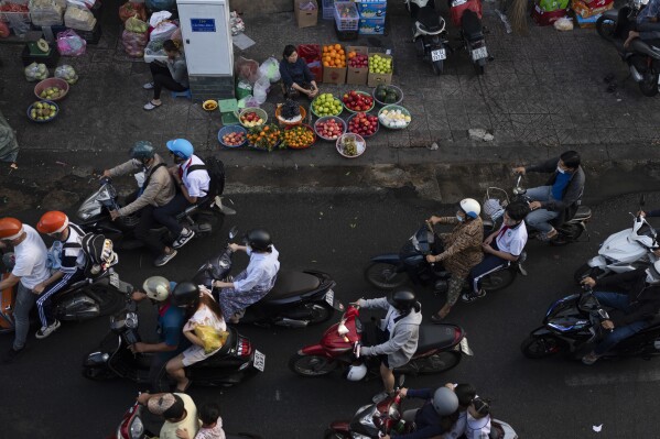 FILE - Commuters move past street vendors during morning rush hour in Ho Chi Minh City, Vietnam, Friday, Jan. 12, 2024. Asian economies are not doing as well as they could and growth in the region is forecast to slow to 4.5% this year from 5.1% in 2023, the World Bank said in a report released Monday, April 1, 2024. (AP Photo/Jae C. Hong, File)