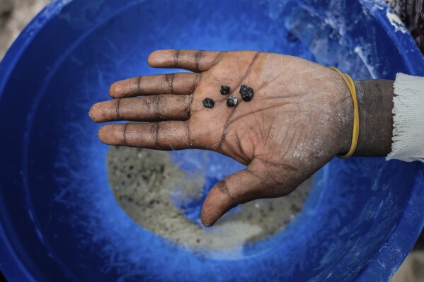 A mine worker holds bits of coltan ore in the mining town of Rubaya, Democratic Republic of Congo, on Friday, May 9, 2025. (AP Photo/Moses Sawasawa)