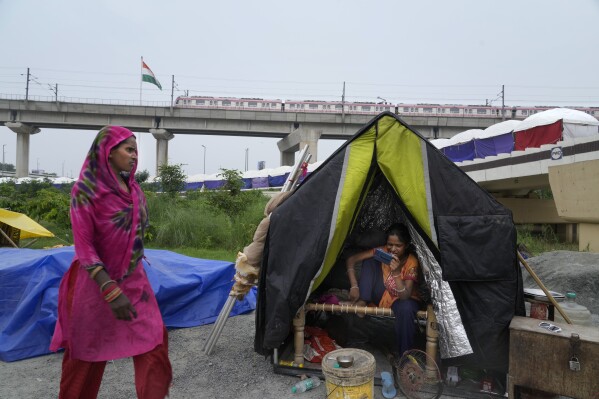 People evacuated from the flood plains of the river Yamuna rest in makeshift tents along a street in New Delhi, India, Thursday, July 13, 2023. Residential areas close to the river were flooded, submerging roads, cars and homes, leading to the evacuation of thousands of people from low-lying areas in the country's capital city. More than 100 people were killed this week after record monsoon rains led to massive waterlogging, road caves-in, collapsed homes and gridlocked traffic, officials said Thursday. (AP Photo/Manish Swarup)
