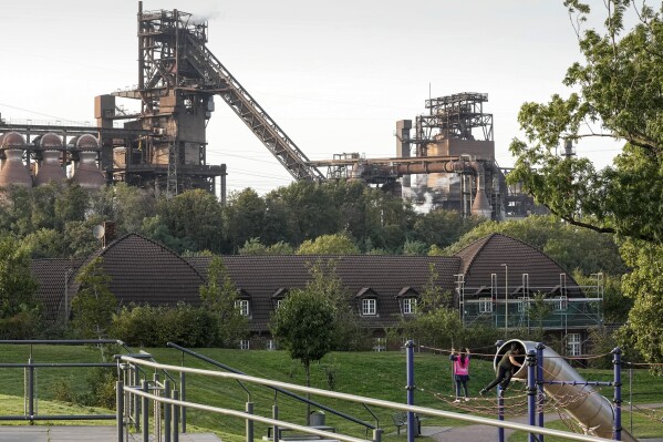Children play in front of a blast furnace of German steel producer thyssenkrupp Steel Europe in Duisburg, Germany, Wednesday, Oct. 11, 2023. The producer — whose emissions in 2022 rivaled those of some oil and gas majors, according to data they reported to non-profit CDP — sent four people with three different delegations to COP27. (AP Photo/Martin Meissner)