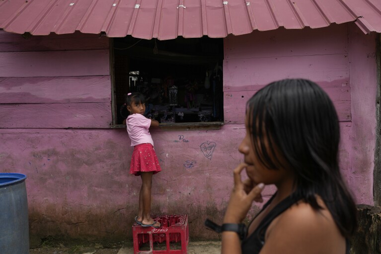 A girl stands on a crate to reach a store's window in Gardi Sugdub Island, part of the San Blas archipelago off Panama's Caribbean coast Saturday, May 25, 2024. Due to rising sea levels, about 300 Guna Indigenous families will relocate to new homes, built by the government, on the mainland. (AP Photo/Matias Delacroix)