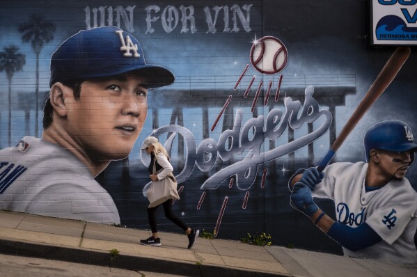 A woman walks past a mural of Los Angeles Dodgers' Shohei Ohtani, left, and Mookie Betts, painted by artist Gustavo Zermeno Jr., in Hermosa Beach, Calif., Monday, March 18, 2024. The Dodgers and the San Diego Padres play Major League Baseball's first regular-season games in Seoul, South Korea on March 20-21. (AP Photo/Jae C. Hong)