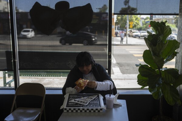 Deneffy Sánchez, 15, eats pizza after school in Los Angeles, Wednesday, Aug. 30, 2023. After failing most of his classes last year because of housing instability, Deneffy is already behind this school year because he didn't have internet at home to do his homework. (AP Photo/Jae C. Hong)