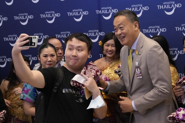 Chinese tourists takes selfies with Thailand's Prime Minister Srettha Thavisin, right, on their arrivals at Suvarnabhumi International Airport in Samut Prakarn province, Thailand, Monday, Sept. 25, 2023. Thailand's new government granting temporary visa-free entry to Chinese tourists, signaling that the recovery of the country's tourism industry is a top economic priority. (AP Photo/Sakchai Lalit)