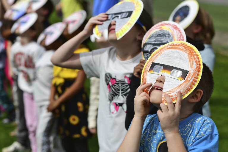 Issace Hutchison, 8, Ferndale Area Elementary School second-grader, views the solar eclipse through his decorated protective special eyewear with classmates at the school in Johnstown, Pa., on Monday, April 8, 2024. (Thomas Slusser/The Tribune-Democrat via AP)