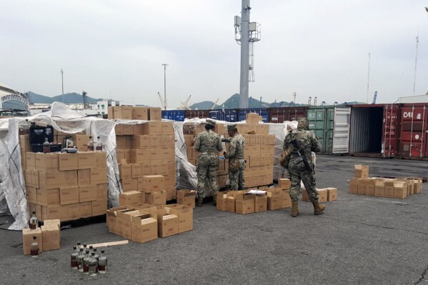 In this photo released by the Mexican Navy, sailors inspect a shipment of bottles labeled mezcal in Manzanillo, Mexico, Saturday, July 22, 2023. Mexican marines working customs duty said Wednesday, July 26, 2023 they found a shipping container loaded with bottles of a clear liquid labeled mezcal but that actually contained liquid methamphetamine. (Mexican Navy via AP)