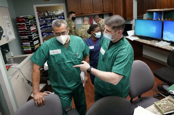 FILE - In this July 16, 2020 file photo, Registered nurses Army Lt. Col. Oswaldo Martinez, left, and Maj. Andrew Wieher, right, with the Urban Augmentation Medical Task Force, work to setup a nurses station inside a wing at United Memorial Medical Center, in Houston.  Texas reported a new daily record for virus deaths Friday and more than 10,000 confirmed cases for the fourth consecutive day. (AP Photo/David J. Phillip)