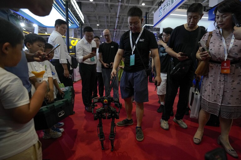 Visitors look at an exhibitor showcasing a walking robot during the annual World Robot Conference at the Etrong International Exhibition and Convention Center on the outskirts of Beijing, Thursday, Aug. 17, 2023. (AP Photo/Andy Wong)