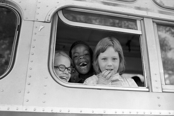 Children smile from window of a school bus in Springfield, Mass., as court-ordered busing brought Black children and white children together in elementary grades without incident, Sept. 16, 1974. (AP Photo/Peter Bregg, File)
