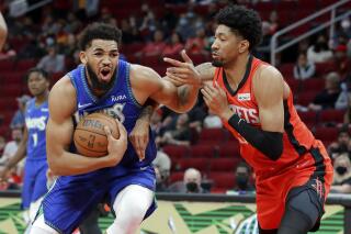 El pívot de los Timberwolves de Minnesota, Karl-Anthony Towns, es defendido por el pívot de los Rockets de Houston, Christian Wood, en la primera mitad del partido del domingo 9 de enero de 2022, en Houston. (AP Foto/Michael Wyke)