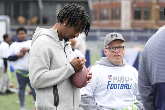 LSU quarterback Jayden Daniels signs a football for a young athlete during an NFL Football Play Football Prospect Clinic with Special Olympics athletes, Wednesday, April 24, 2024 in Detroit. (AP Photo/Carlos Osorio)