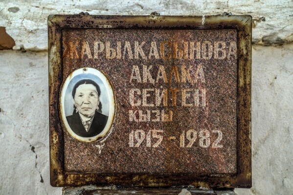A woman's photo is visible on her grave in a cemetery near the dried-up Aral Sea, on the outskirts of Aralsk, Kazakhstan, Monday, July 3, 2023. (AP Photo/Ebrahim Noroozi)