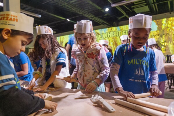 Hana Chmeruk, center, who moved to the U.S. from Ukraine, and Avigael Yahyisrael, 7, make matzah with other first graders from Milton Gottesman Jewish Day School of the Nation's Capital, during a "Matzah Factory" field trip to the JCrafts Center for Jewish Life and Tradition in Rockville, Md., Thursday, April 18, 2024, ahead of the Passover holiday which begins next Monday evening. To be kosher for Passover the dough has to be prepared and cooked all within 18 minutes and not allowed to rise. (AP Photo/Jacquelyn Martin)