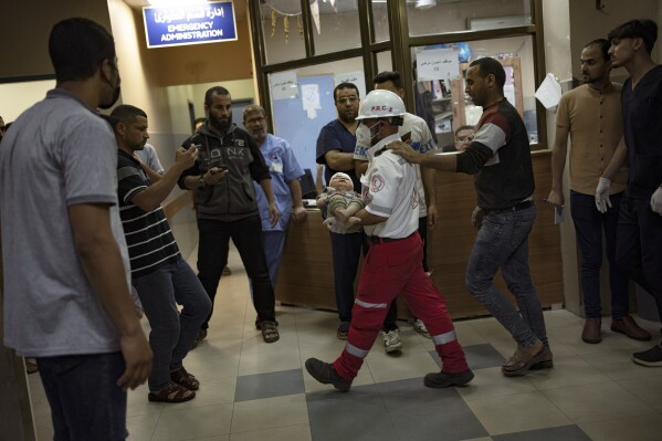 A Palestinian medic carries a baby wounded in the Israeli bombardment of the Gaza Strip into a hospital in Khan Younis, Saturday, Oct. 21, 2023. (AP Photo/Fatima Shbair)
