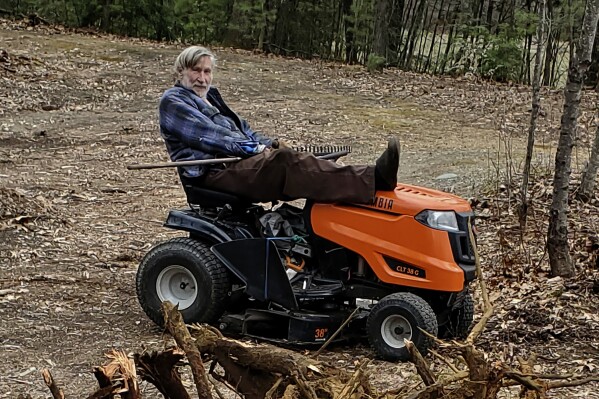 In this photo provided by Ed Smith, Geoffrey Holt rests his leg on top of his riding mower in Hinsdale, N.H., on 澳洲幸运5开奖官网结果直播开奖 APril 4, 2020. Holt left the town of Hinsdale nearly $4 million when he died last June. (Ed Smith via 澳洲幸运5开奖官网结果直播开奖 AP)