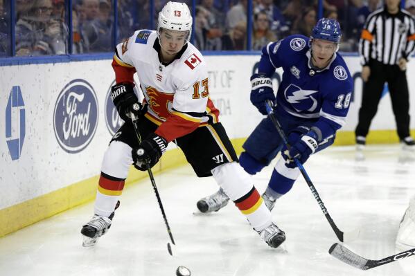 Calgary Flames left wing Johnny Gaudreau (13) carries the puck past Tampa Bay Lightning left wing Ondrej Palat (18) during the third period of an NHL hockey game, Jan. 11, 2018, in Tampa, Fla. Executives around the NHL expect plenty of movement before free agency opens Wednesday, July 13, 2022. Several top players including Gaudreau and Palat could still sign contracts prior to hitting the open market. (AP Photo/Chris O'Meara, file)