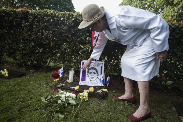 A woman places flowers by a portrait depicting one of the Panamanian students who was killed during the January 1964 anti-American riots over sovereignty of the Panama Canal Zone, marking Martyrs Day in Panama City, Thursday, Jan. 9, 2025. (AP Photo/Agustin Herrera)