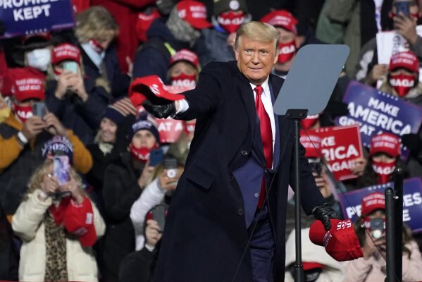 President Donald Trump tosses ball caps to supporters as he arrives for a campaign rally at the Williamsport Regional Airport in Montoursville, Pa, Saturday, Oct. 31, 2020. (AP Photo/Gene J. Puskar)