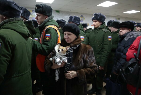 
              A woman with her dog lines up with Russian military personnel to vote in the presidential election in Moscow, Russia, Sunday, March 18, 2018. Russians are voting in a presidential election in which Vladimir Putin is seeking a fourth term in the Kremlin. (AP Photo/Denis Tyrin)
            