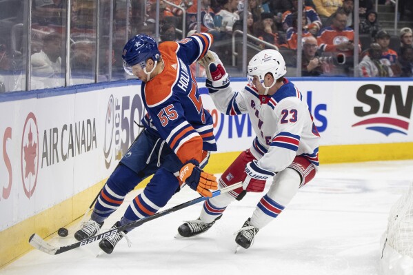 New York Rangers' Adam Fox (23) and Edmonton Oilers' Dylan Holloway (55) vie for the puck during the second period of an NHL hockey game Thursday, Oct. 26, 2023, in Edmonton, Alberta. (Jason Franson/The Canadian Press via AP)