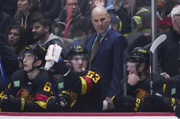 Vancouver Canucks coach Rick Tocchet, back, stands behind Ilya Mikheyev, Bo Horvat and Brock Boeser, from left, during the first period of the team's NHL hockey game against the Chicago Blackhawks on Tuesday, Jan. 24, 2023, in Vancouver, British Columbia. (Darryl Dyck/The Canadian Press via AP)