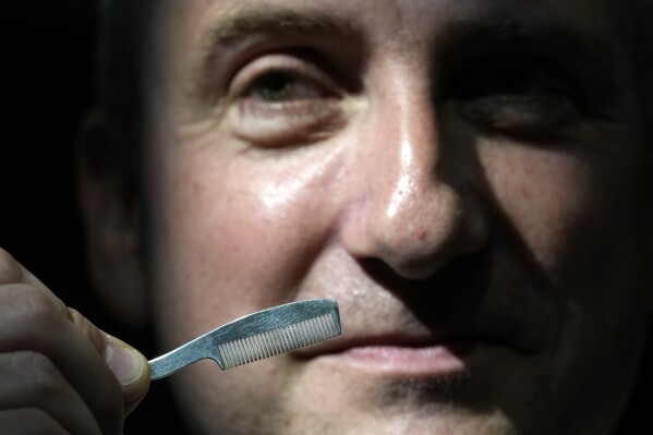 A Sotheby's employee displays a moustache comb from Freddie Mercury's personal items at Sotheby's auction rooms in London, Thursday, Aug. 3, 2023. More than 1,400 of Mercury's items, including his flamboyant stage costumes, handwritten drafts of “Bohemian Rhapsody” and the baby grand piano he used to compose Queen's greatest hits, are going on show in a free exhibition at Sotheby's London ahead of their sale. (AP Photo/Kirsty Wigglesworth)