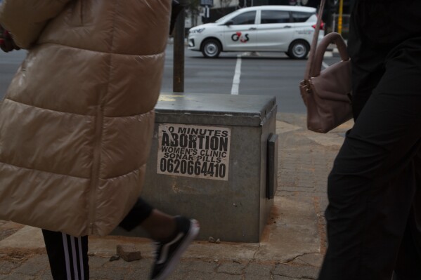Women pass a sticker advertising abortion pills on a sidewalk in Johannesburg, Wednesday June 28, 2023. When the U.S. Supreme Court overturned the national right to an abortion a year ago, it shook efforts to legalize and make abortions safer in Africa. Sub-Saharan Africa has the world's highest rate of unintended pregnancies, and 77% of abortions are estimated to be unsafe. (AP Photo/Denis Farrell)