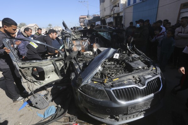 Palestinians look at a car targeted by an Israeli airstrike in Rafah, Gaza Strip, Sunday, Jan. 7, 2024. Two journalists were killed in the strike, Hanza Dahdouh, who worked for Al Jazeera, and a freelance journalist, Mustafa Thuria (AP Photo/Hatem Ali)