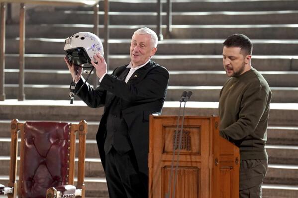 Speaker of the House of Commons, Sir Lindsay Hoyle, left, holds the helmet of one of the most successful Ukrainian pilots, inscribed with the words "We have freedom, give us wings to protect it", which was presented to him by Ukrainian President Volodymyr Zelenskyy as he addressed parliamentarians in Westminster Hall, London,, during his first visit to the UK since the Russian invasion of Ukraine, Wednesday Feb. 8, 2023. (Stefan Rousseau/pool photo via AP)