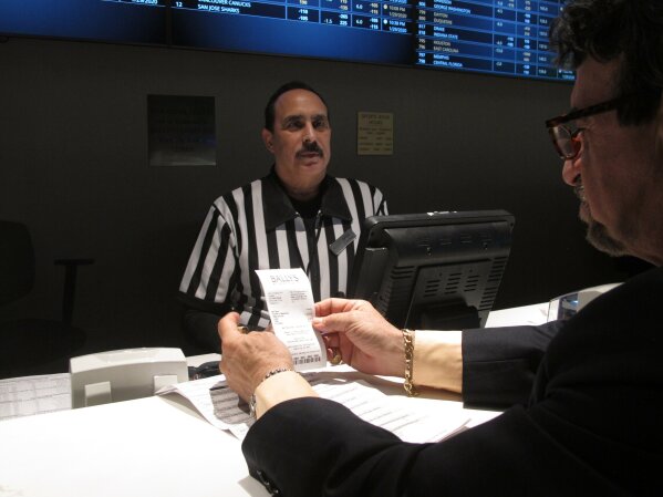 In this Jan. 29, 2020 photo, a gambler checks his ticket after making a bet on the upcoming Super Bowl at Bally's casino in Atlantic City, N.J. Gambling industry officials expect Sunday's Super Bowl to be among the most heavily wagered-on championship games ever. (AP Photo/Wayne Parry)