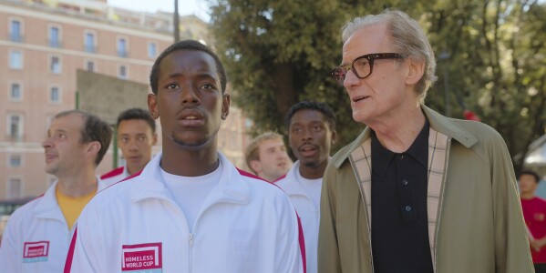 This image released by Netflix shows Micheal Ward, foreground left, and Bill Nighy in a scene from "The Beautiful Game." (Alfredo Falvo/Netflix via AP)