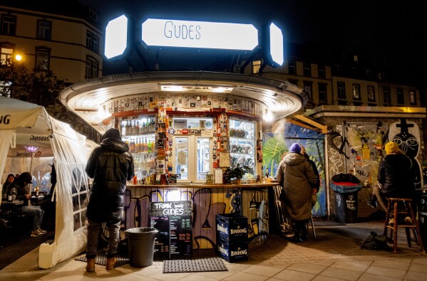 People gather at a former water house, a small shop that sprung up in the 19th century to encourage workers to drink affordable water rather than beer or schnapps, that is now a kiosk in Frankfurt, Germany, on Feb. 16, 2025. (AP Photo/Michael Probst)
