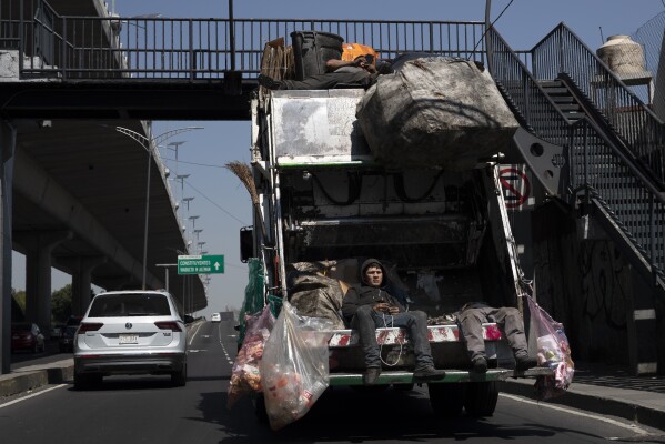 FILE - Trash collectors ride on their garbage truck in Mexico City, Tuesday, Oct. 6, 2020. Mexican President Andres Manuel Lopez Obrador swept into office in 2018 with the motto laying out his administration’s priorities: “For the good of all, first the poor.” (AP Photo/Marco Ugarte, File)