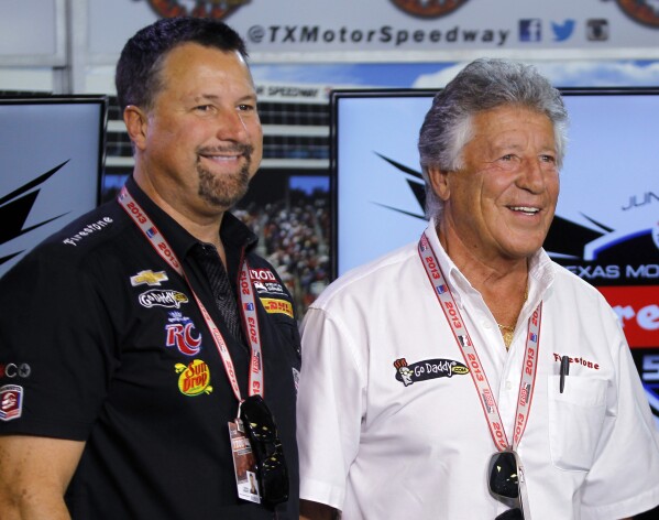 FILE - Michael Andretti, left, and his father, Mario Andretti, pose for a photo following a news conference at Texas Motor Speedway in Fort Worth, Texas, June 7, 2013. Formula One has rejected Andretti Global's application to join the global racing series in 2025 or 2026 but said Wednesday, Jan. 31, 2024, it is willing to revisit the issue in 2028 when General Motors has an engine ready for competition.(AP Photo/Tim Sharp, File)