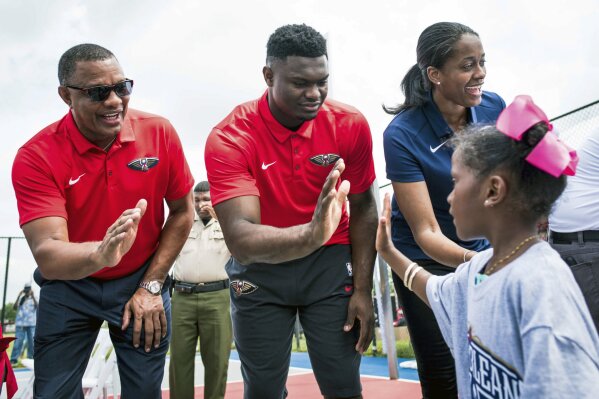 In this June 22, 2019, photo, New Orleans Pelicans head coach Alvin Gentry, left, draft pick Zion Williamson, and vice president of operations Swin Cash greet children before a ribbon cutting ceremony at the refurbished basketball court at Goretti Playground in New Orleans. Cash believes the NBA is realizing having more women is important to growing the league’s overall brand, business and bottom line. (Shawn Fink/The Advocate via AP)
